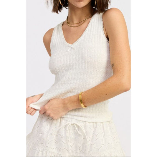 Woman wearing a white sleeveless top with a plain background