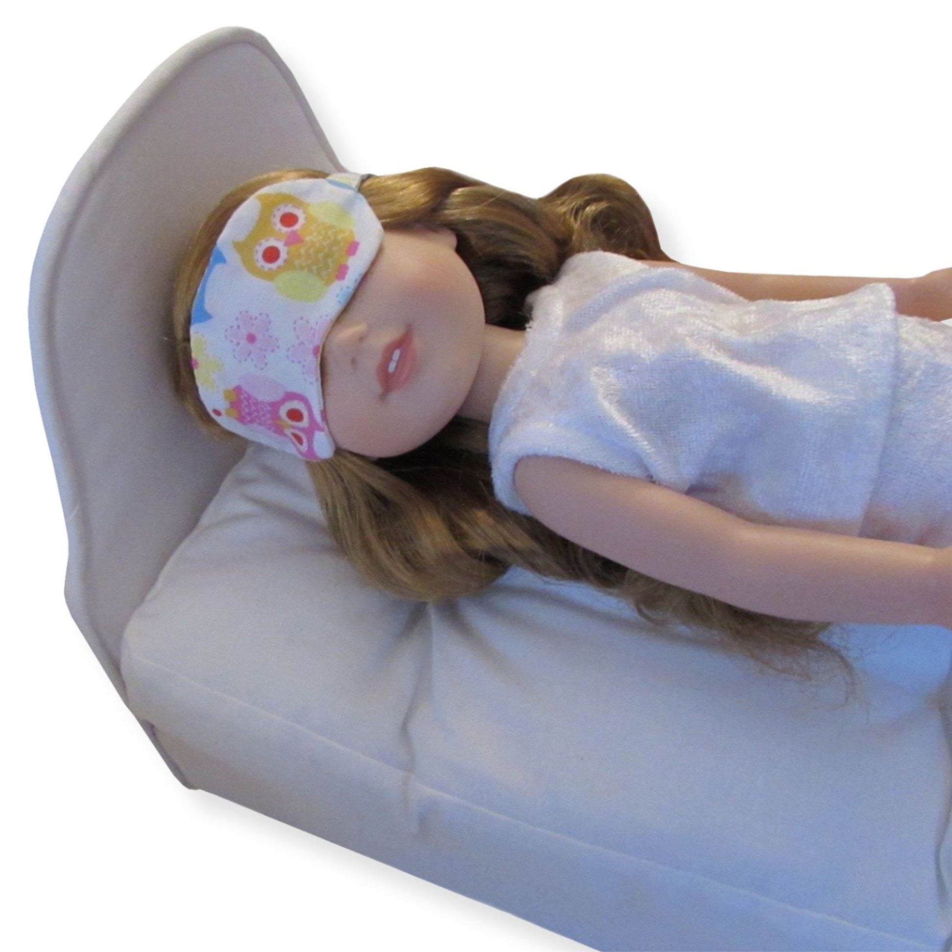 Doll wearing a colorful owl-patterned eye mask on a white background