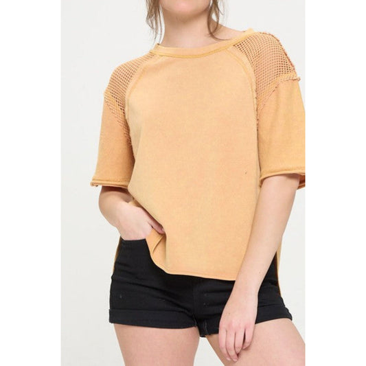 Person wearing a mustard yellow top with mesh sleeves on a white background