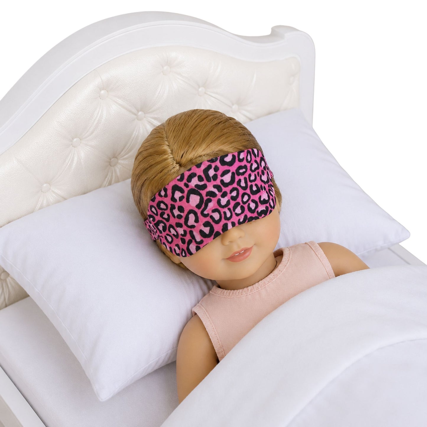 Doll wearing a pink leopard print sleep mask in bed