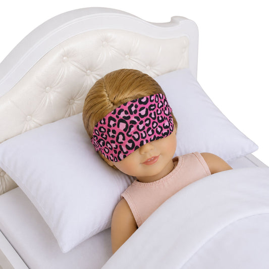 Doll wearing a pink leopard print sleep mask in bed