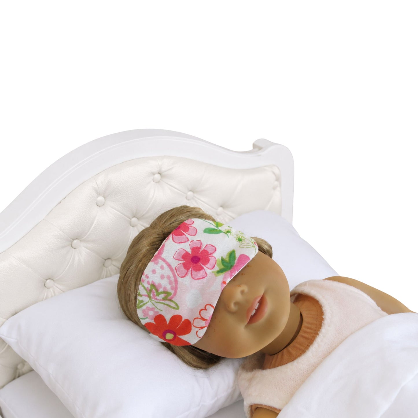 Doll wearing a floral sleep mask on a white bed