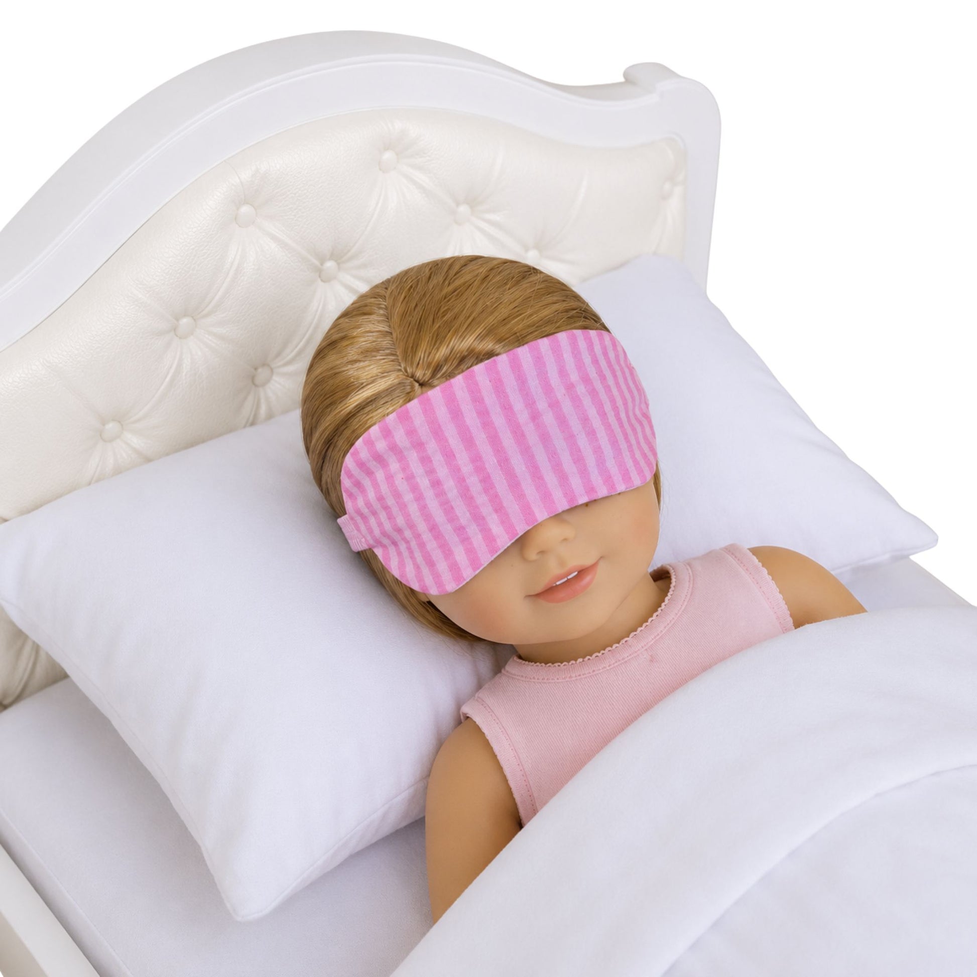 A 14.5-inch doll wearing a pink striped eye mask on a white bed
