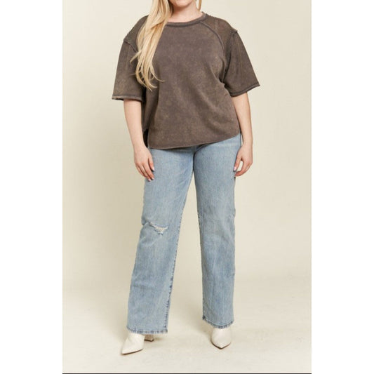 Person wearing a brown oversized shirt and light blue jeans on a beige background