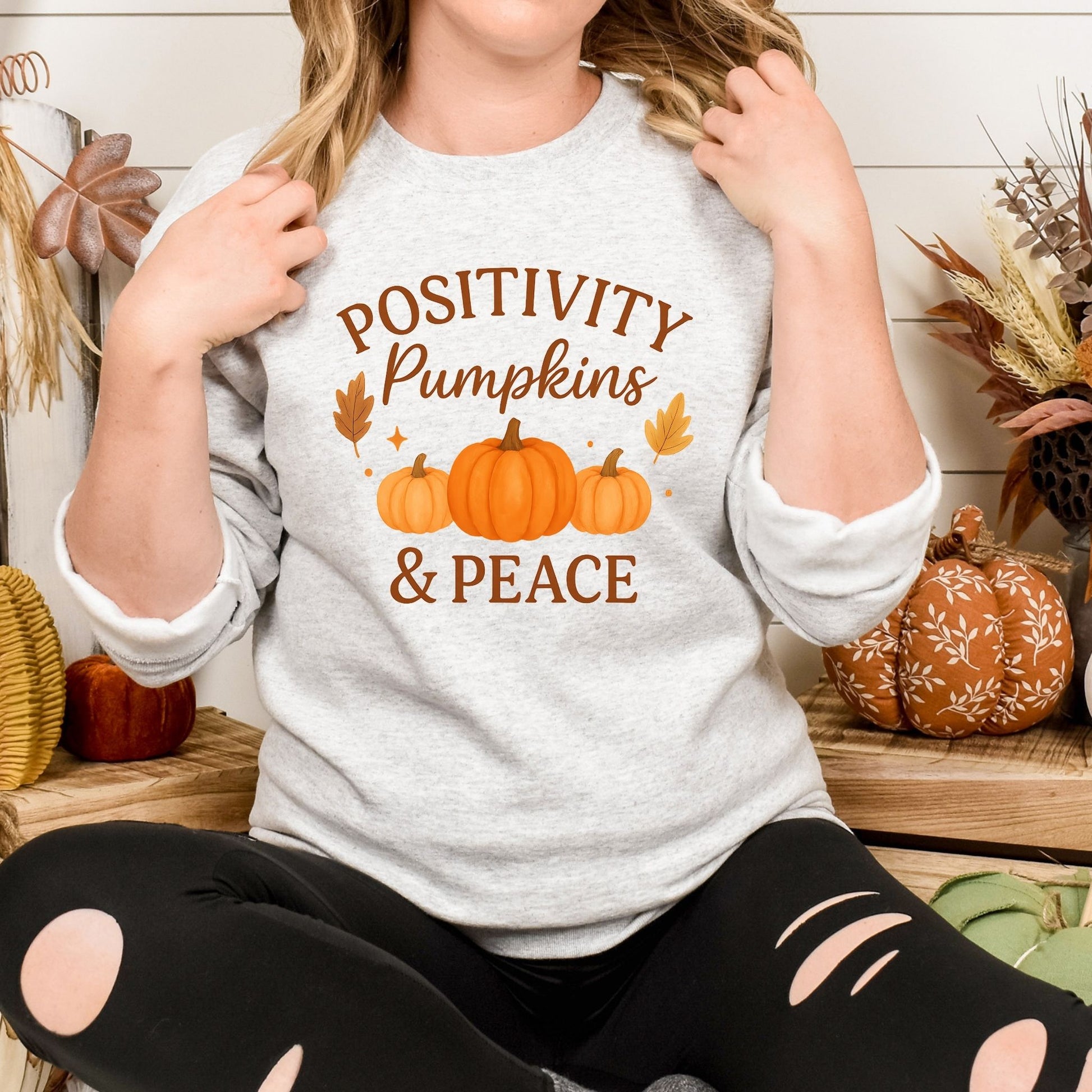 Person wearing a shirt with 'Positivity Pumpkins & Peace' text and pumpkin graphics.