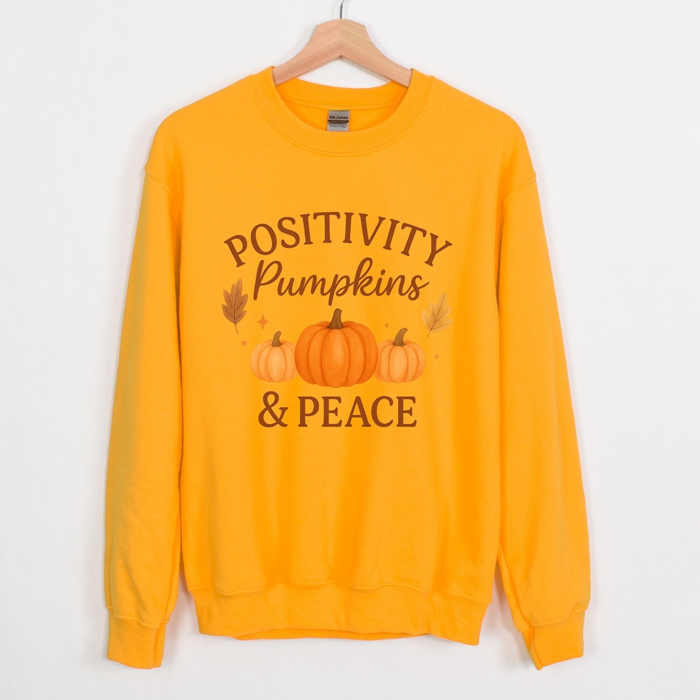 Gold sweatshirt with 'Positivity Pumpkins & Peace' text on a white background