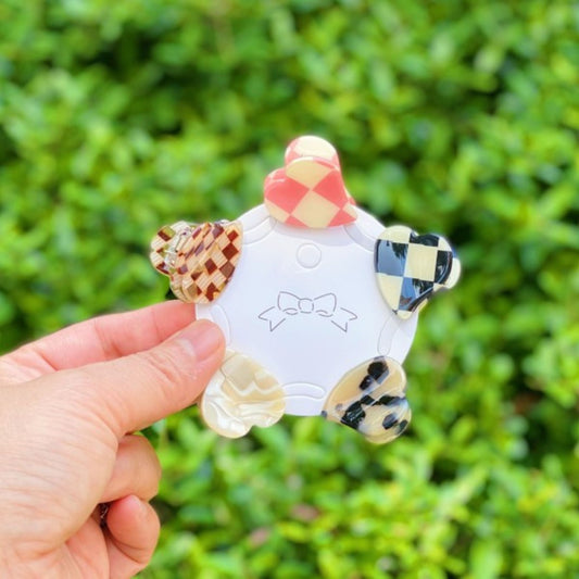 Colorful ceramic rooster figurine held against a green leafy background