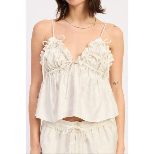 Woman wearing a white ruffled top with thin straps on a white background