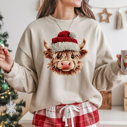 Person wearing a beige sweatshirt with a cow design and Santa hat, holding a mug in a festive setting.
