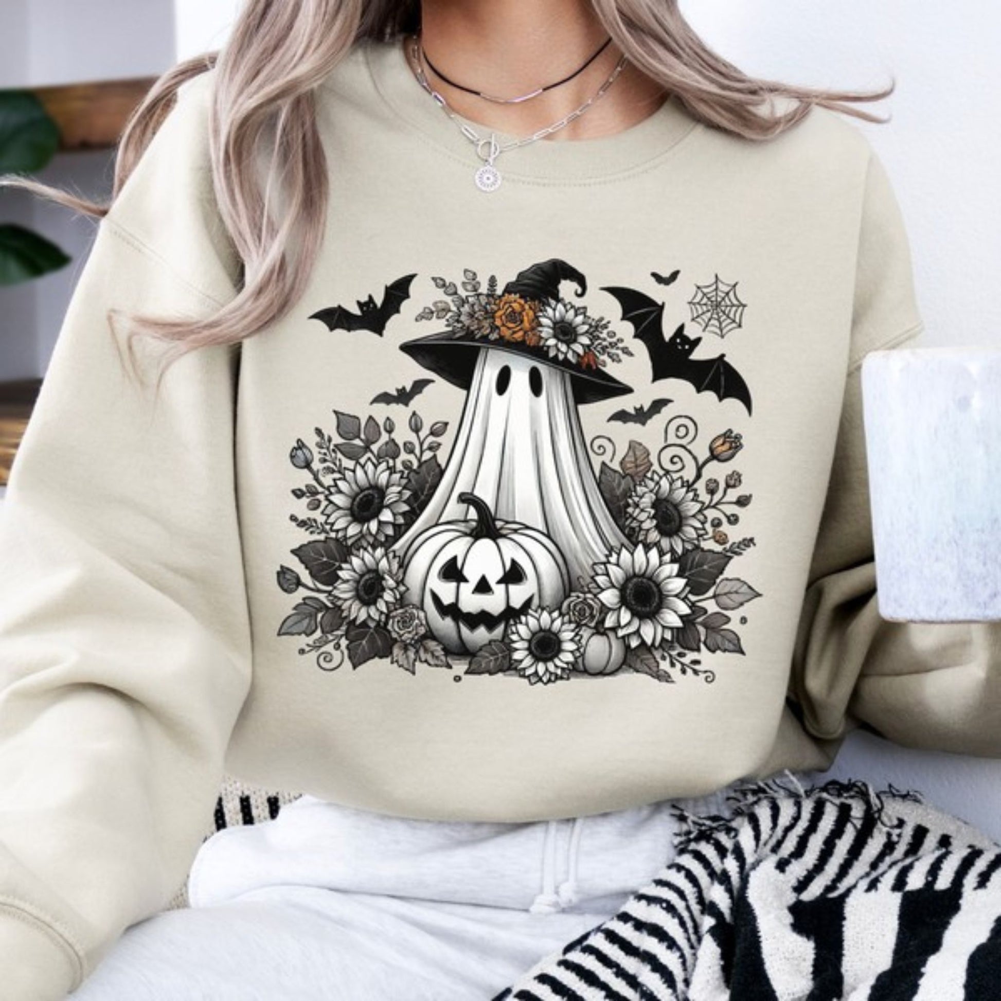 Beige sweatshirt with Halloween-themed design featuring a ghost, pumpkin, and flowers.