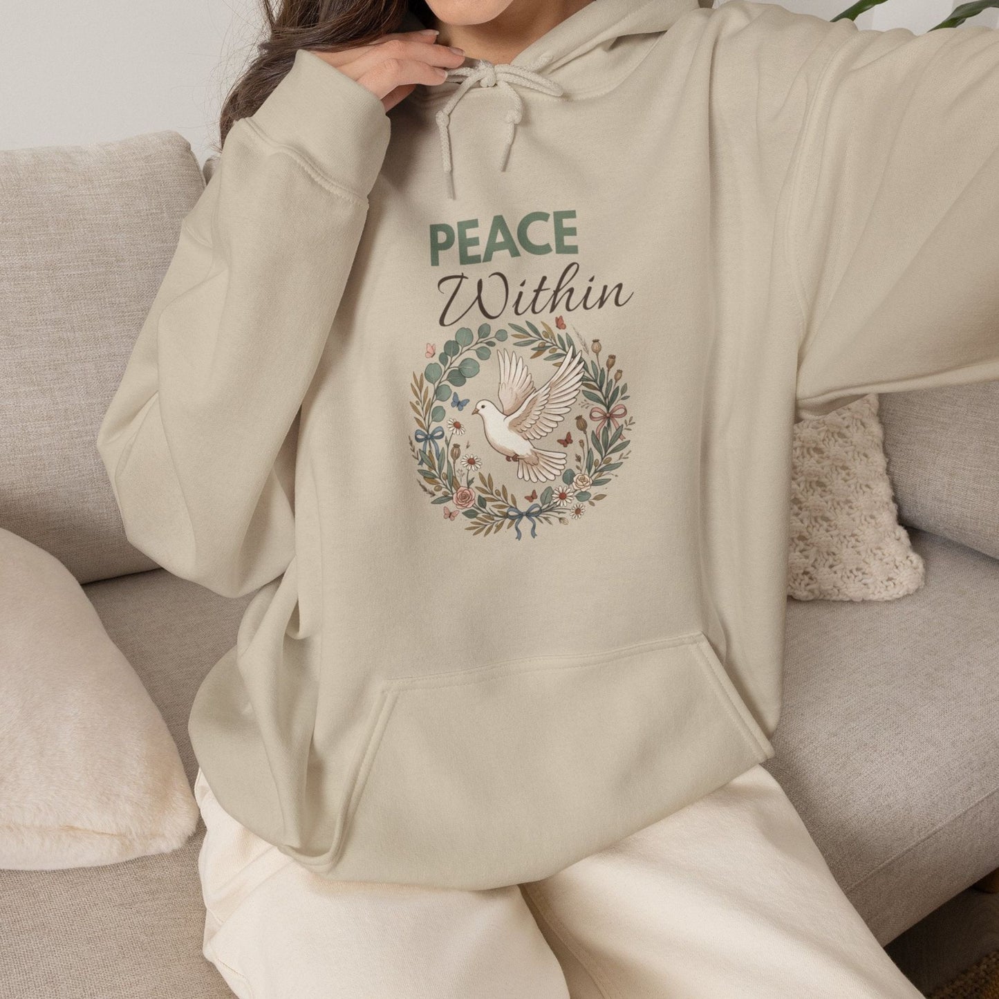 A woman is wearing a sand-colored hooded sweatshirt with 'PEACE Within' on the front.