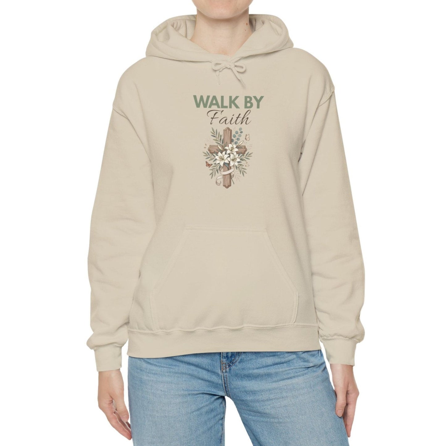 A woman is wearing a sand colored hooded sweatshirt with 'WALK BY Faith' on the front.