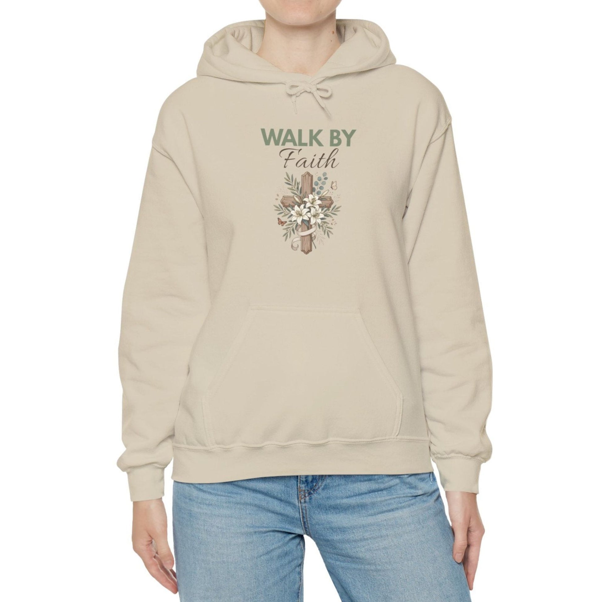 A woman is wearing a sand colored hooded sweatshirt with 'WALK BY Faith' on the front.