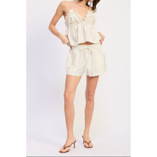 Woman wearing a babydoll top with drawstring shorts.