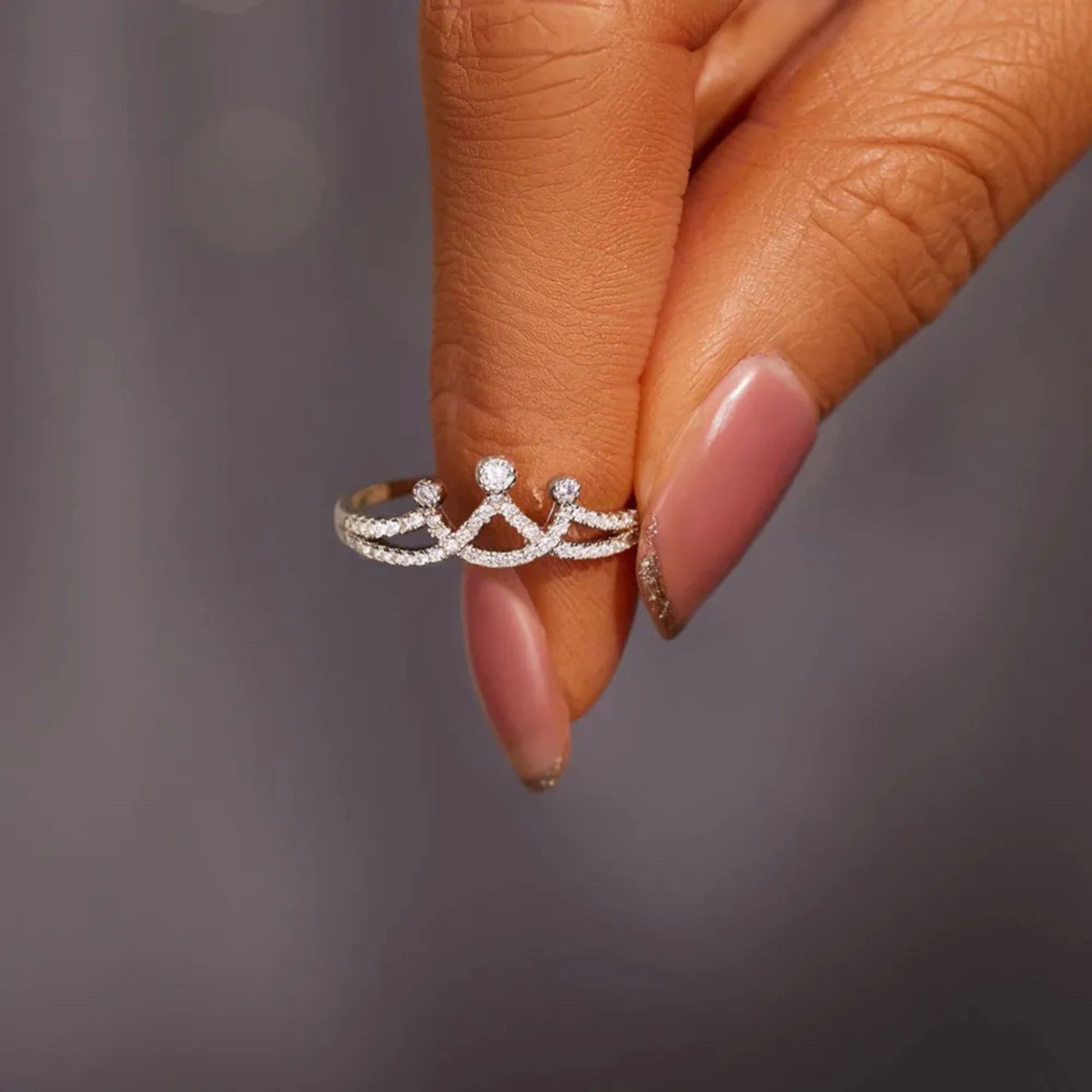 A woman is holding a silver crown shaped inlaid Zircon 925 Sterling Silver ring.