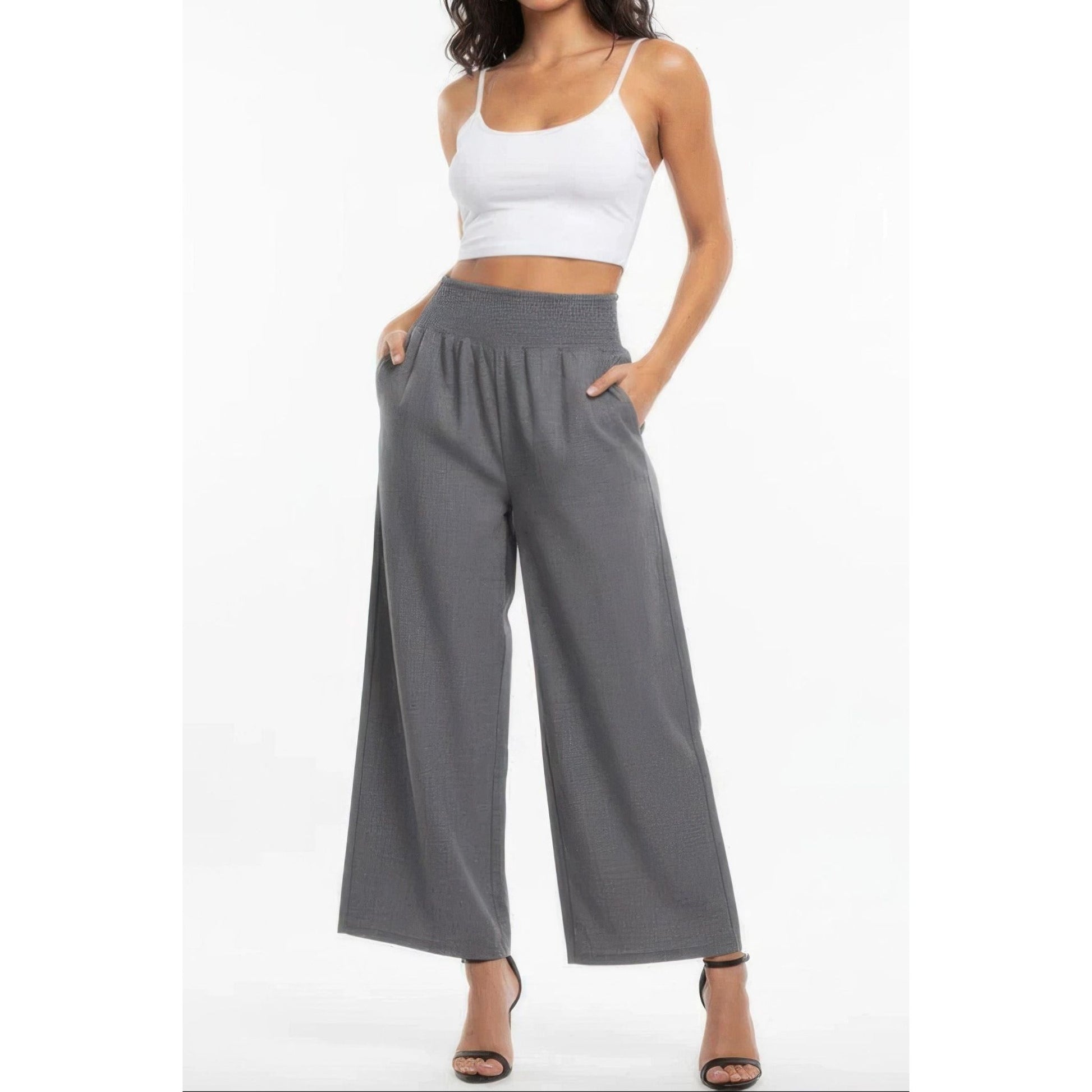 Woman wearing a white crop top and gray wide-leg pants on a white background
