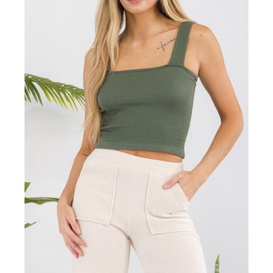 Woman wearing a green crop top and beige pants with a white background