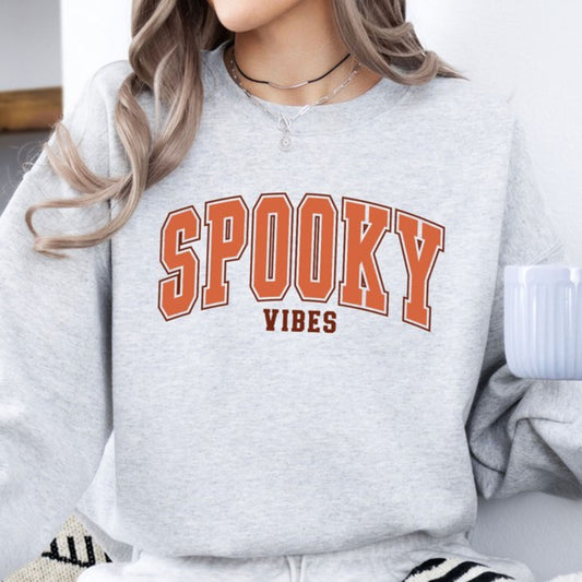 Gray sweatshirt with 'SPooky Vibes' text worn by a person.