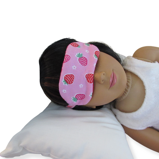 Doll wearing a pink headband with strawberry pattern on a white background