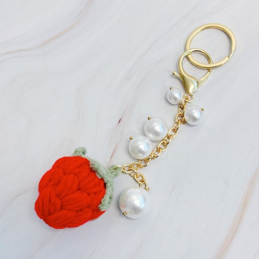 Keychain with red strawberry charm and pearl beads on a white background