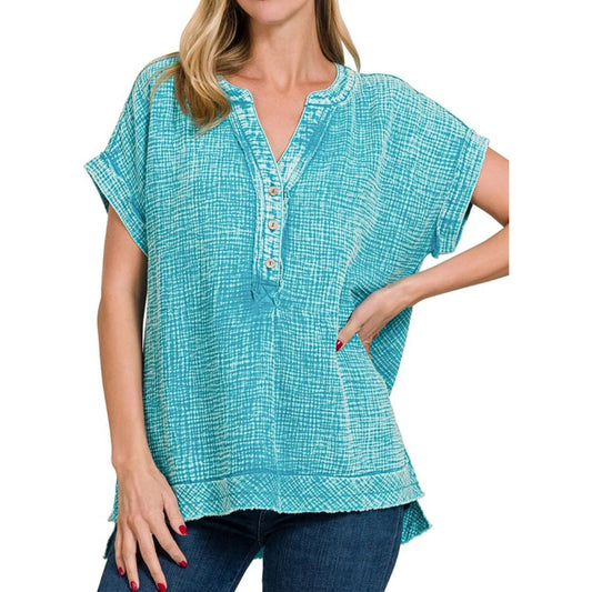 Woman wearing a turquoise patterned top on a white background