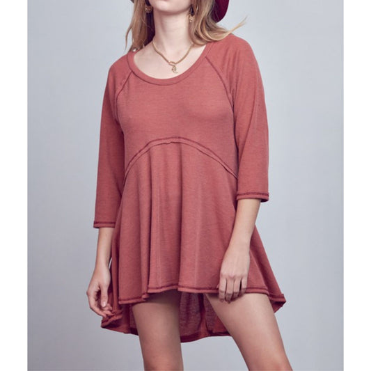 Person wearing a rust-colored dress against a plain background