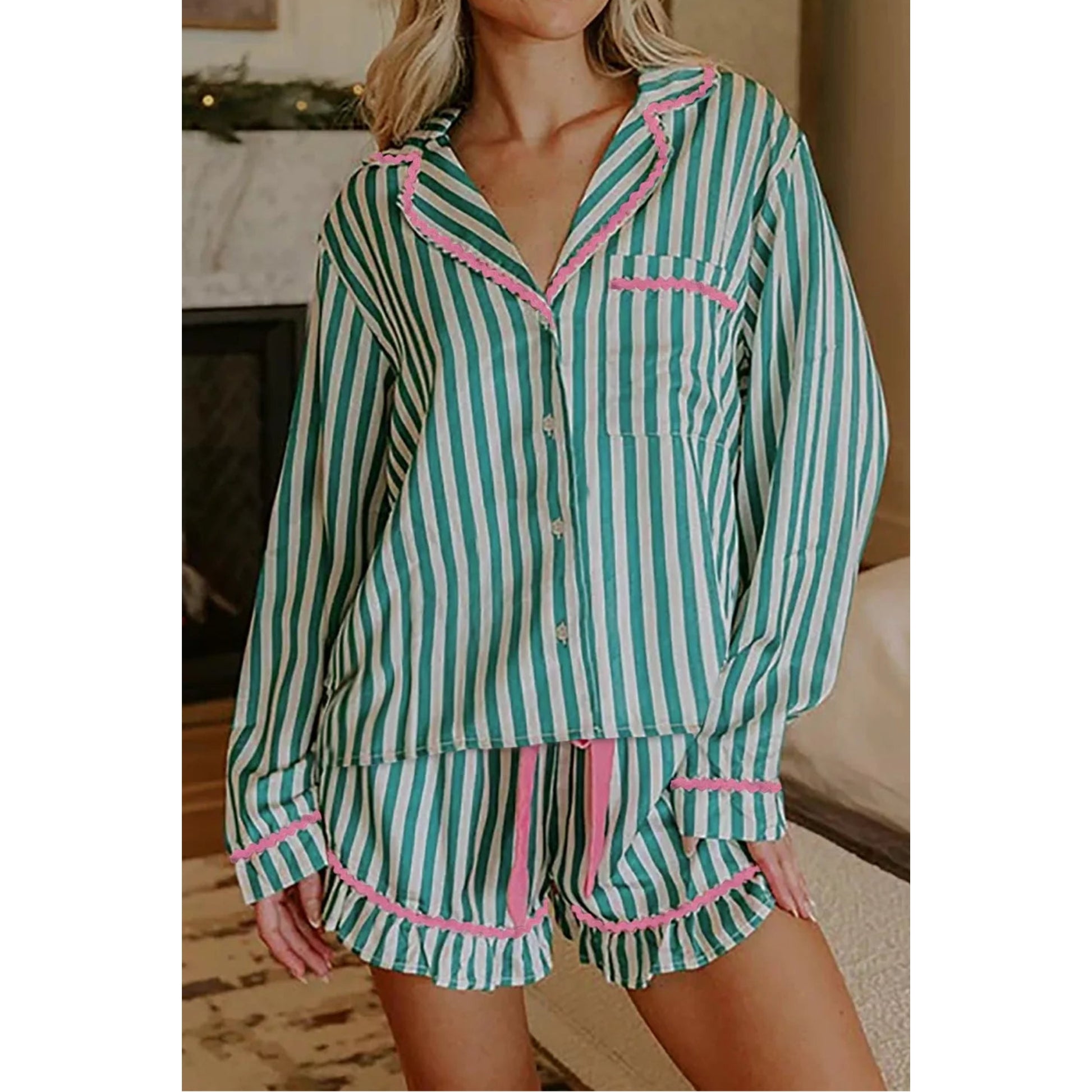 A woman wearing a two-piece pajama set with turquoise and white vertical stripes and pink ruffle trim, shown in a home interior setting.