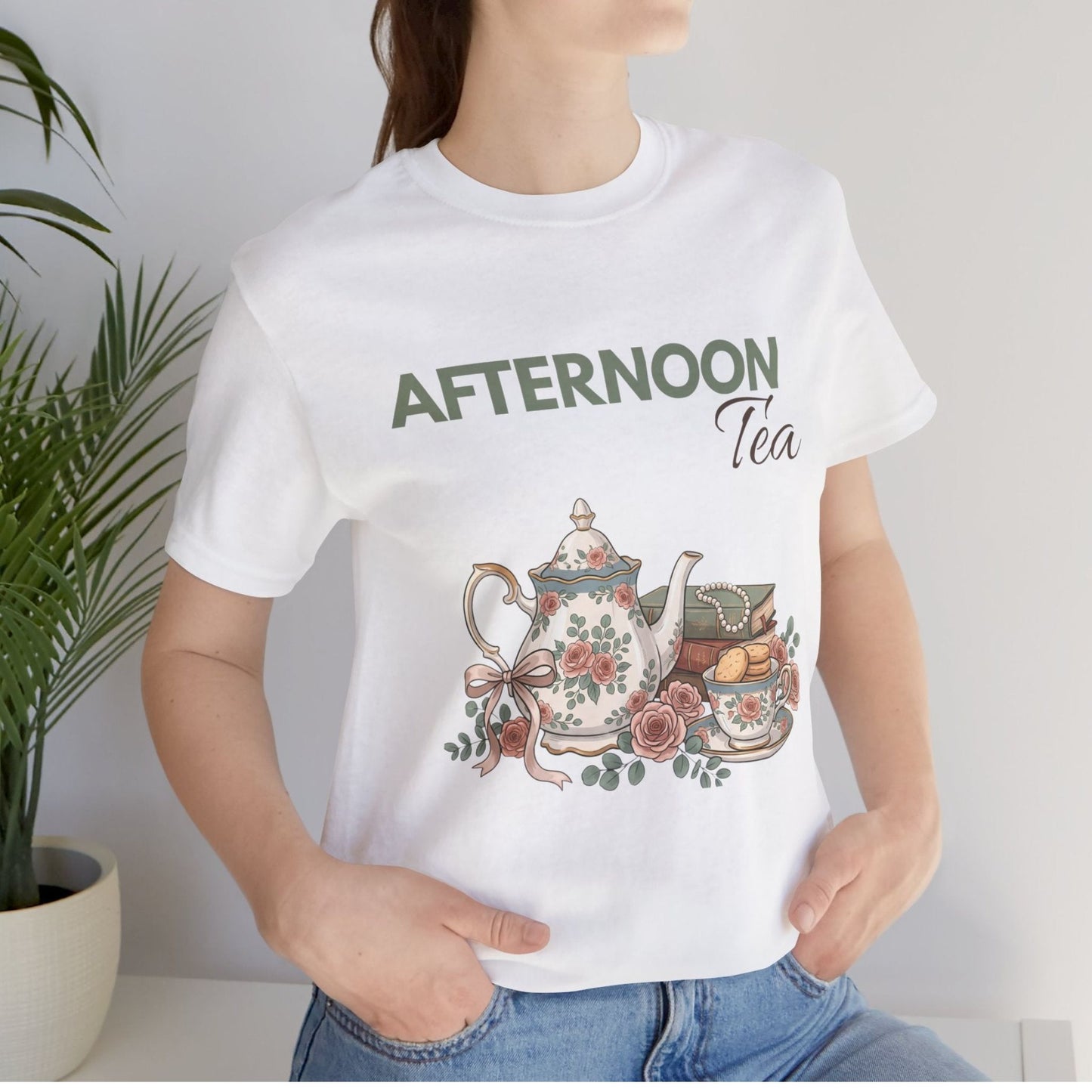 A woman is standing by a plant with a white t-shirt with 'AFTERNOON Tea' on the front.