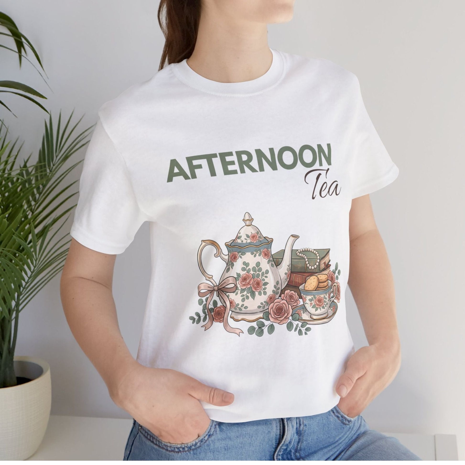 A woman is standing by a plant with a white t-shirt with 'AFTERNOON Tea' on the front.
