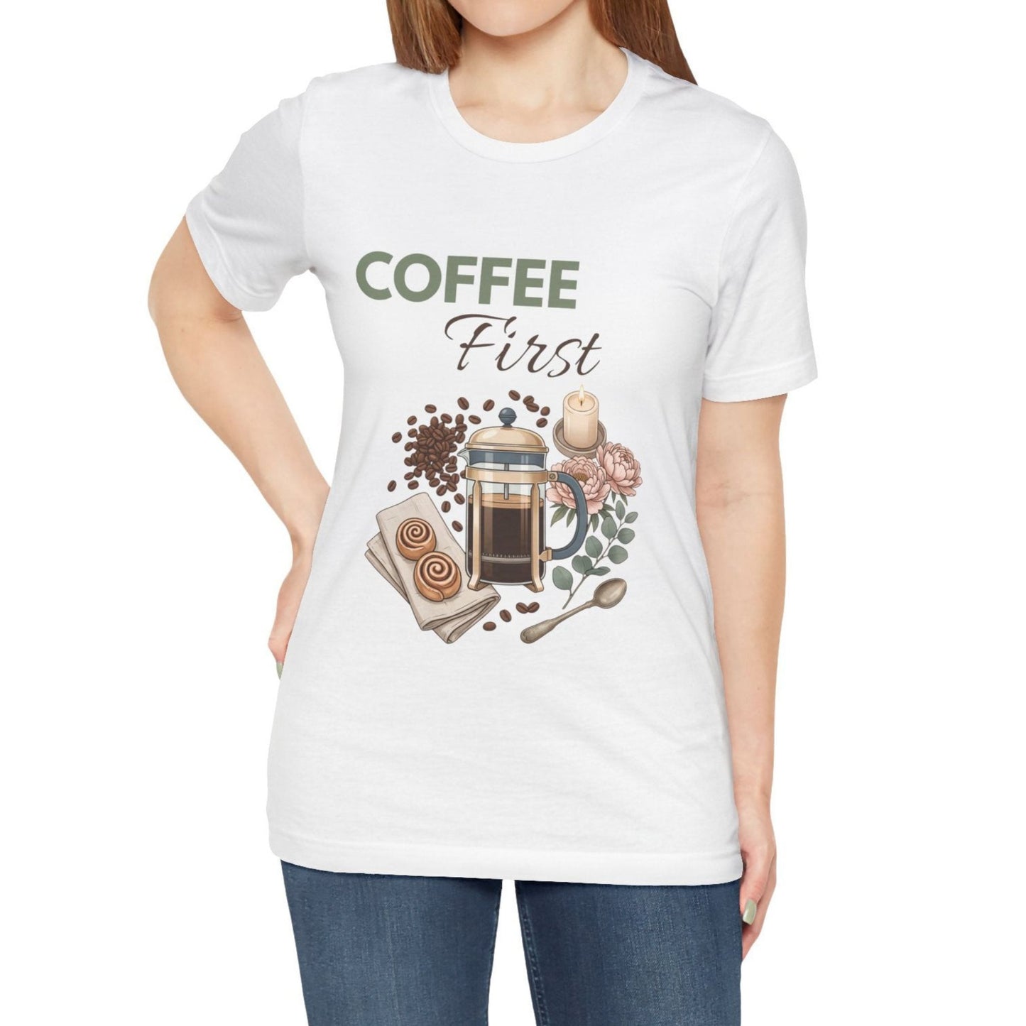 White t-shirt with 'Coffee First' graphic design featuring a French press, coffee beans, and other coffee-related items.