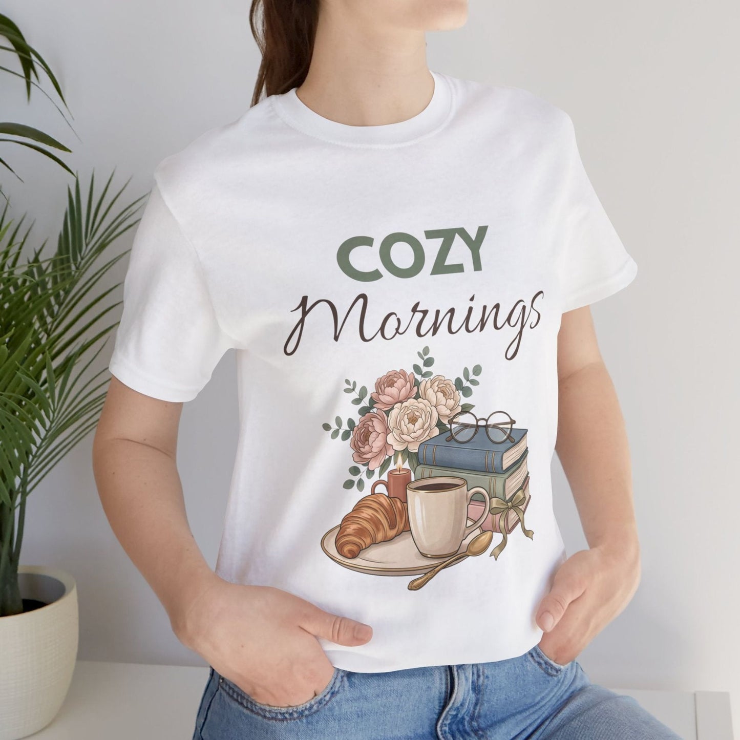 A woman wearing a white t-shirt with  'Cozy Mornings'.