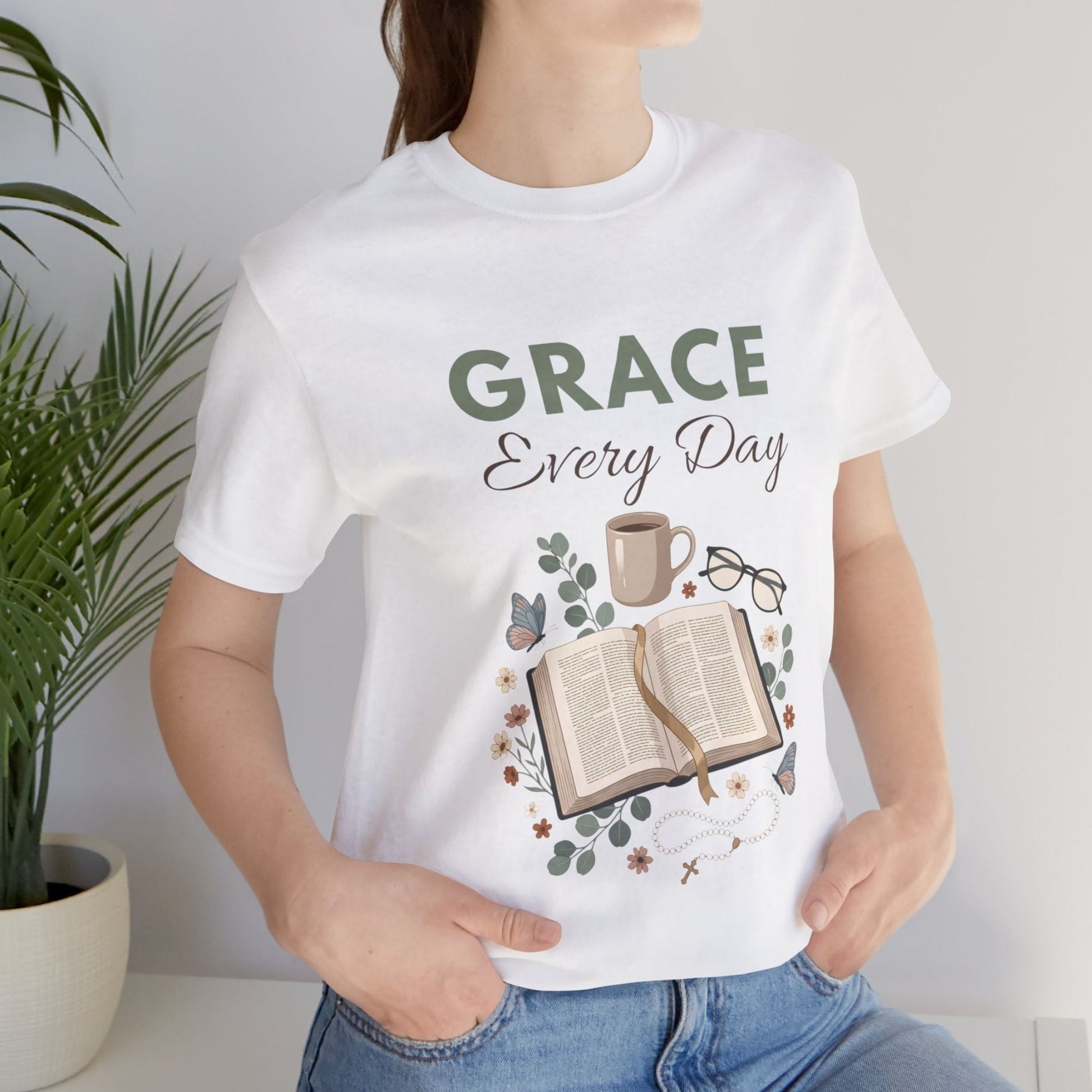 Person wearing a white t-shirt with 'Grace Every Day' design, sitting indoors.