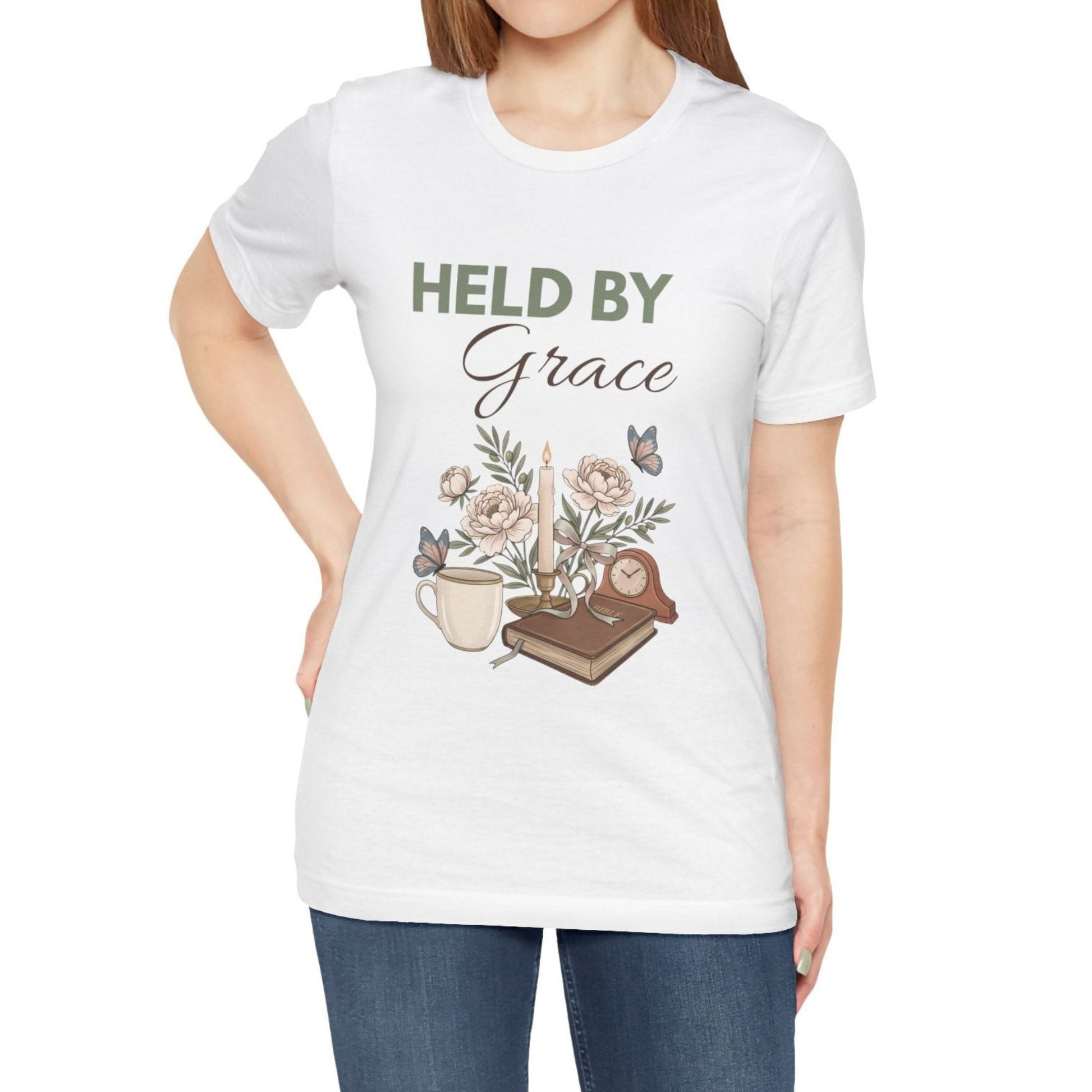 White t-shirt with 'HELD BY Grace' text and floral design worn by a person on a white background