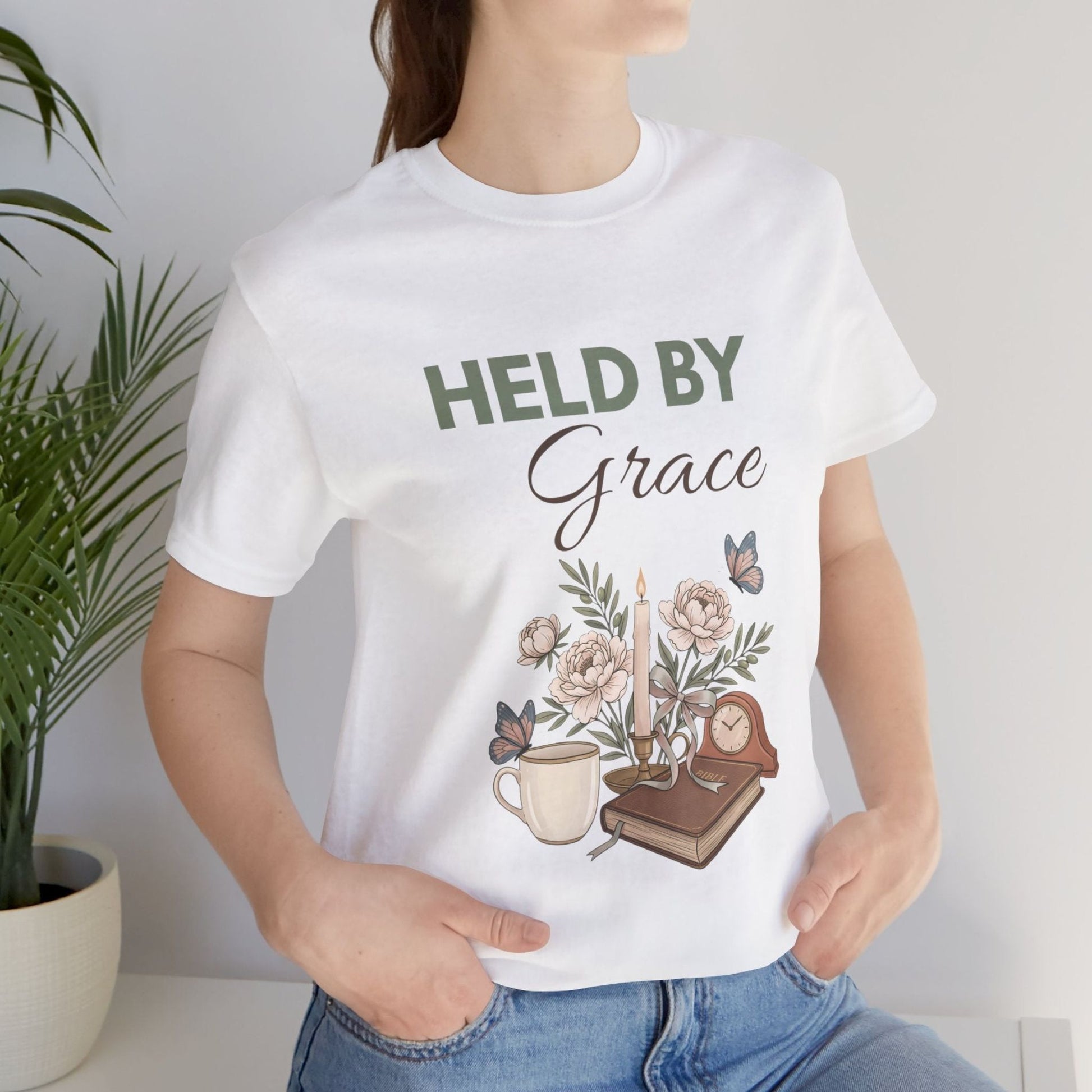 A woman wearing a  white "Held By Grace" t-shirt.