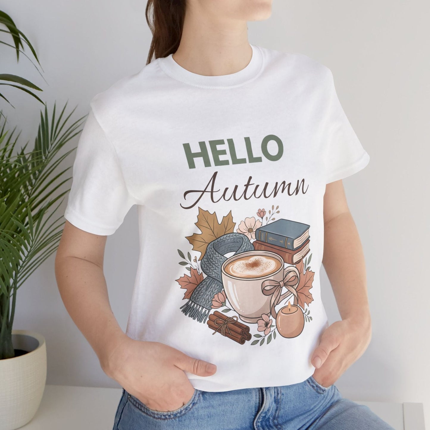 Person wearing a white t-shirt with 'Hello Autumn' design featuring a cup of coffee and autumn elements.