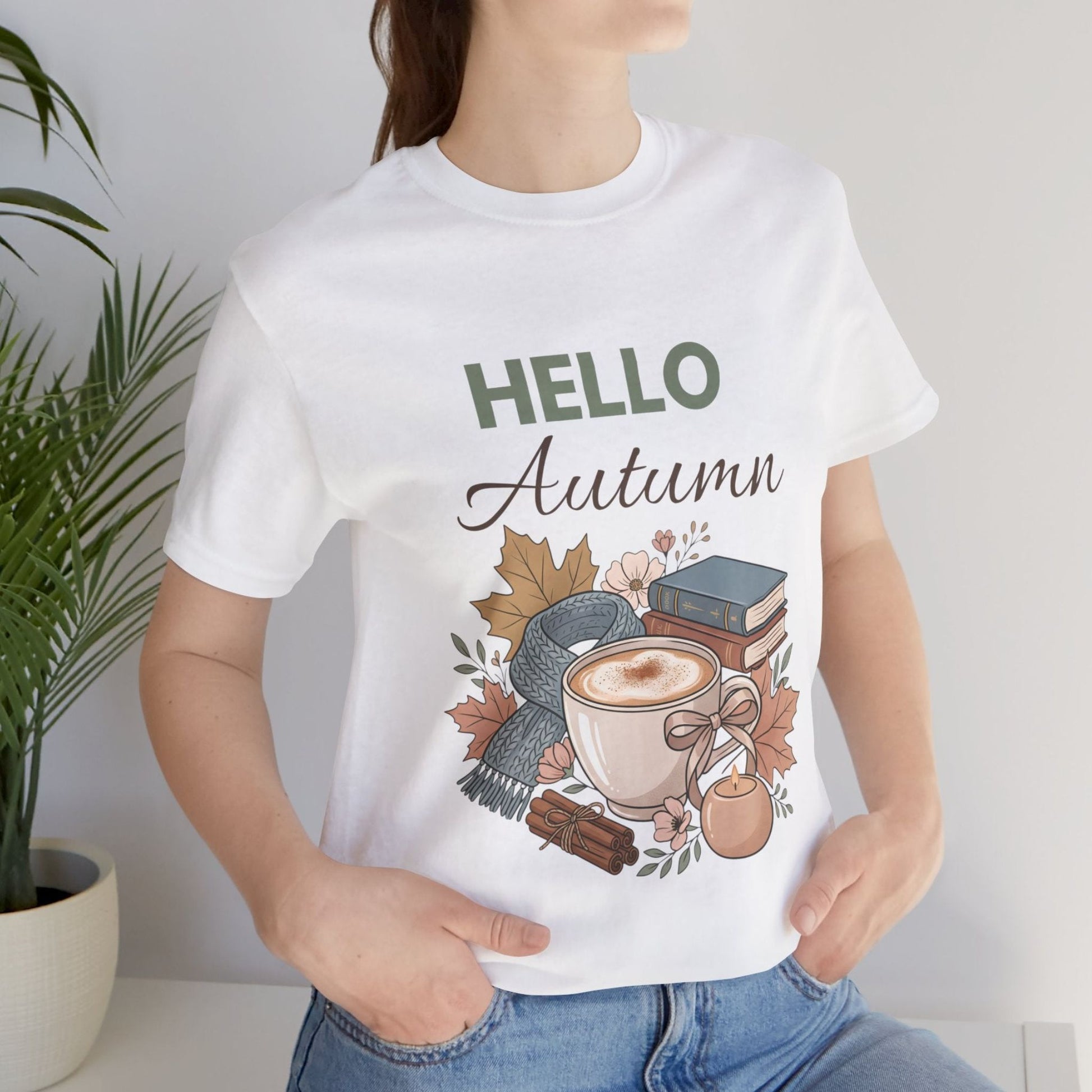 Person wearing a white t-shirt with 'Hello Autumn' design featuring a cup of coffee and autumn elements.