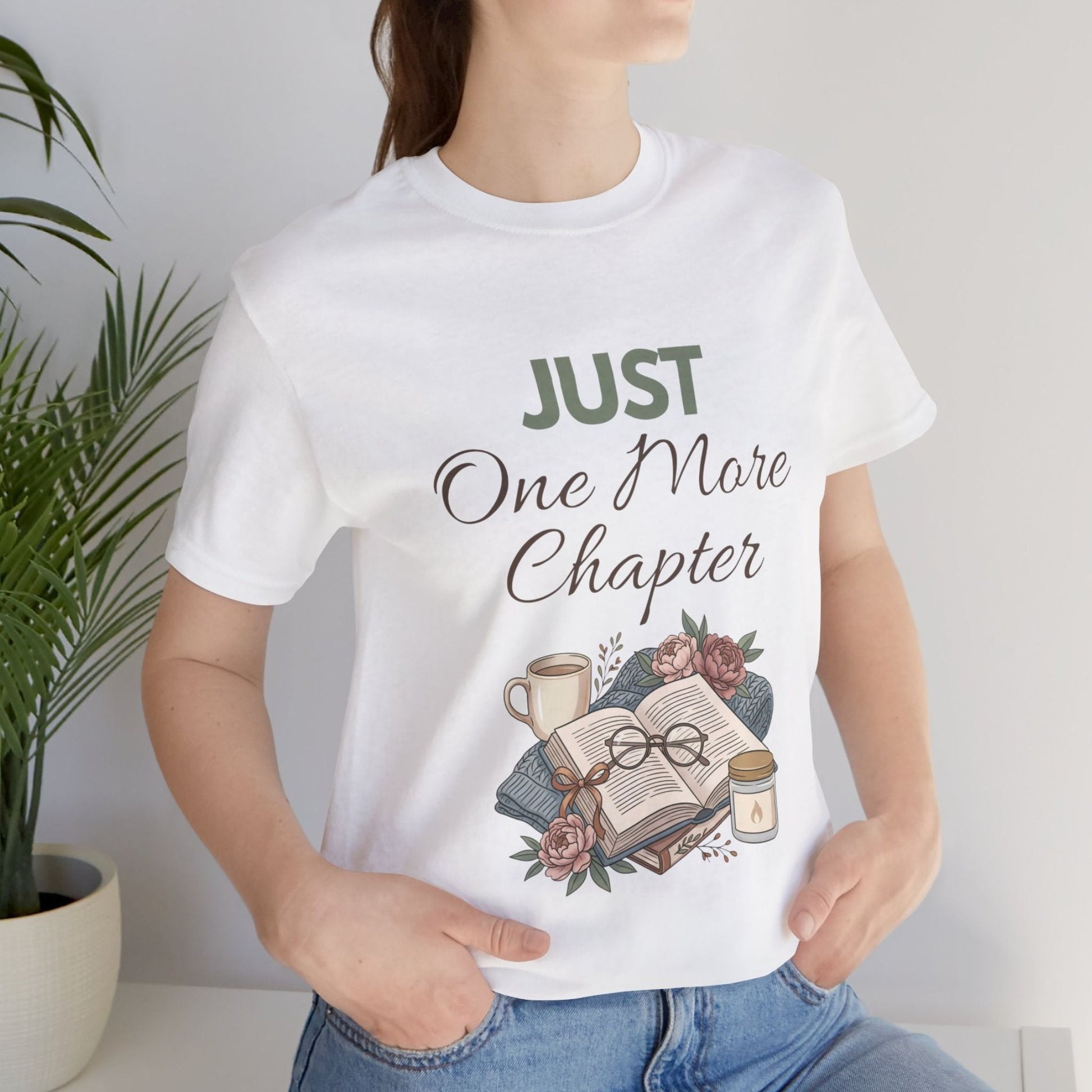 Person wearing a white t-shirt with 'Just One More Chapter' design, holding a plant.