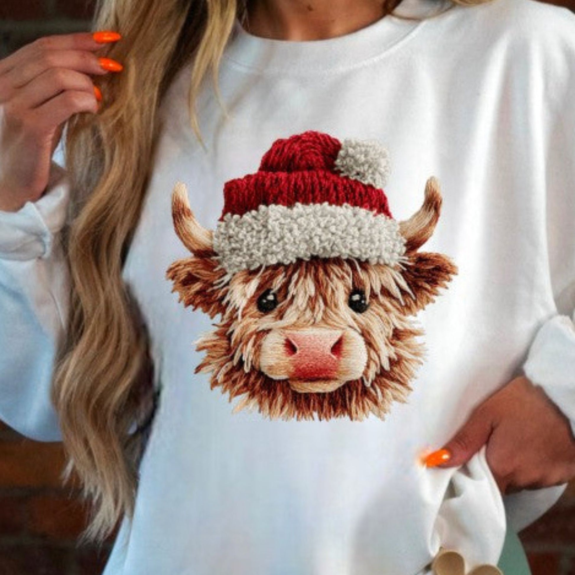 White sweatshirt with a highland cow wearing a Santa hat design.