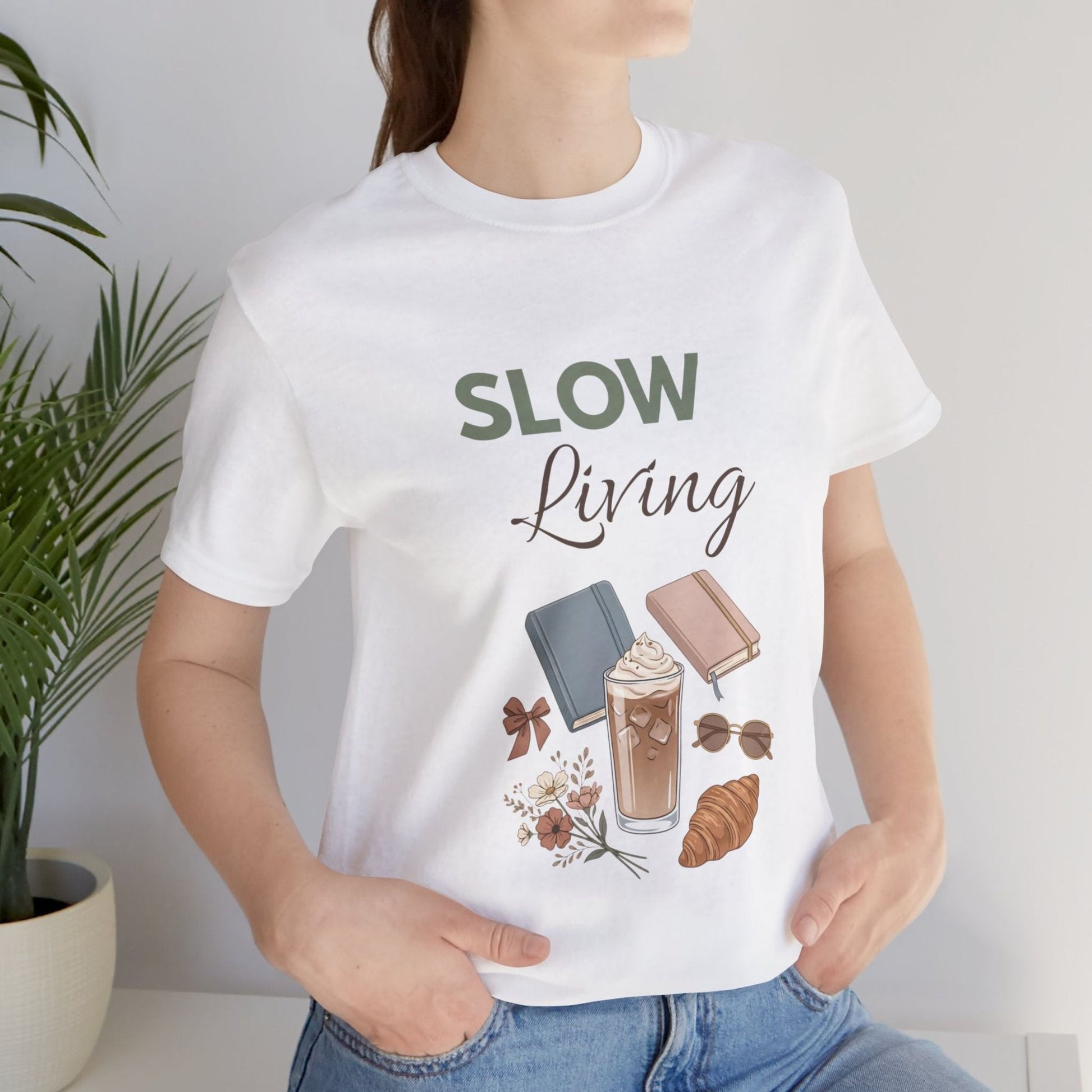 Person wearing a white t-shirt with 'SLOW Living' design, holding a plant.