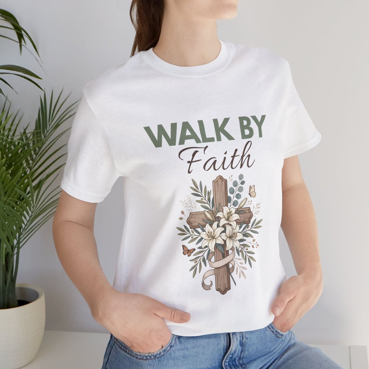 Person wearing a white t-shirt with 'Walk by Faith' design, standing against a plain background.