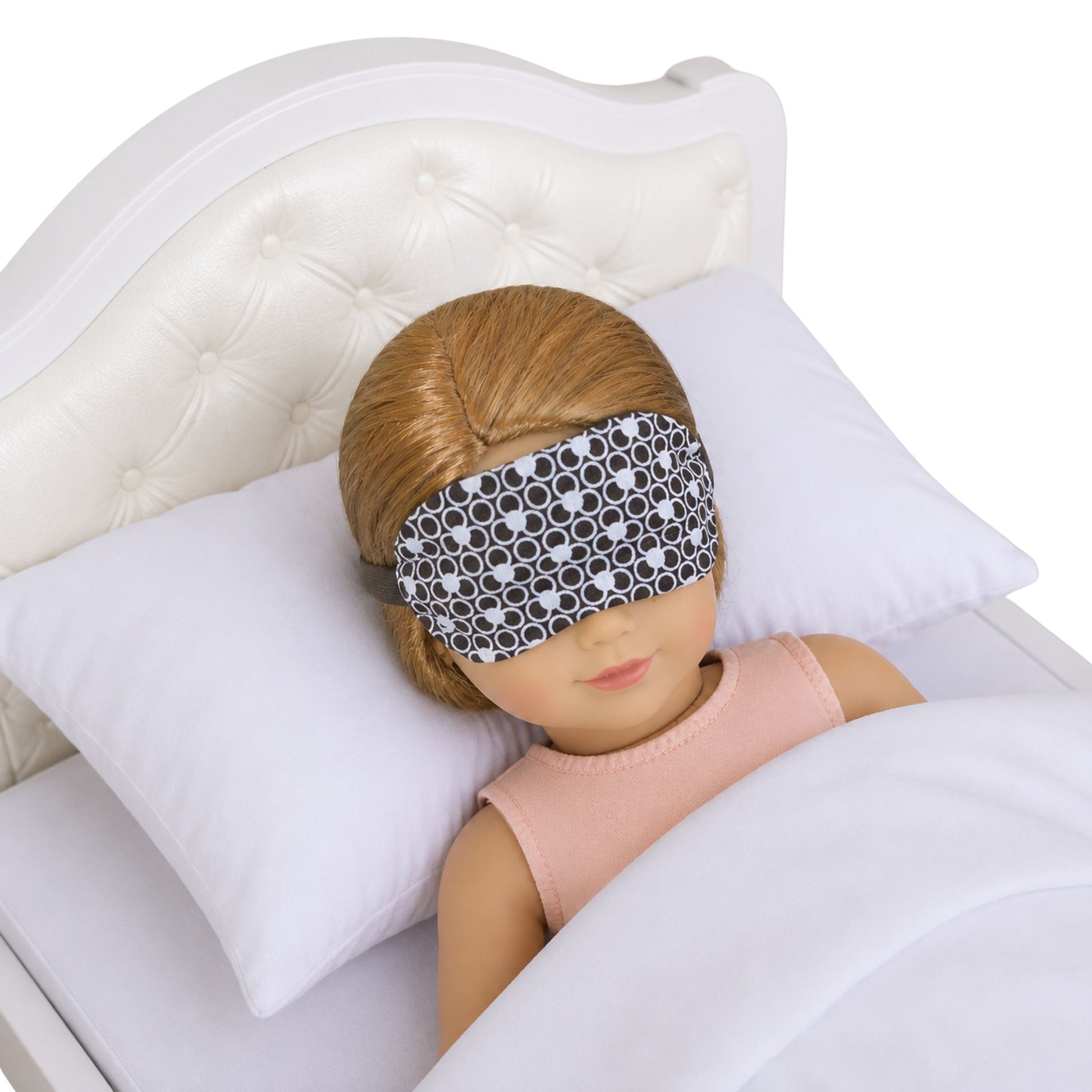 Doll wearing a patterned sleep mask on a bed